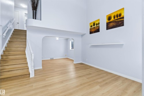 Unfurnished living room with arched walkways, stairway, light wood-type flooring, and a towering ceiling - 115 Deer Ridge Drive, St. Albert, AB - Indoor Photo Showing Other Room