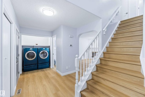 Foyer entrance featuring stairs, a textured ceiling, light wood-style floors, and washer and clothes dryer - 115 Deer Ridge Drive, St. Albert, AB - Indoor Photo Showing Other Room