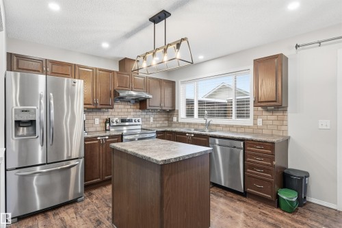 Kitchen with appliances with stainless steel finishes, decorative light fixtures, a center island, backsplash, and dark wood-style flooring - 21017 60 Avenue, Edmonton, AB - Indoor Photo Showing Kitchen With Stainless Steel Kitchen With Double Sink With Upgraded Kitchen