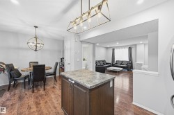 Kitchen featuring dark brown cabinets, pendant lighting, a kitchen island, a textured ceiling, and dark wood-type flooring - 