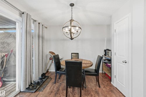 Dining space featuring a chandelier, dark wood-style floors, and a textured ceiling - 21017 60 Avenue, Edmonton, AB - Indoor Photo Showing Dining Room