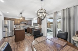 Kitchen with appliances with stainless steel finishes, hanging light fixtures, a kitchen island, decorative backsplash, and a textured ceiling - 