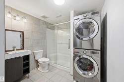 Full bath featuring estacked washer and dryer, tile walls, a stall shower, light tile patterned flooring, and vanity - 