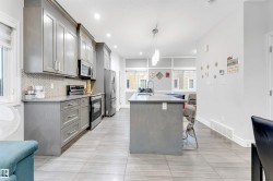 Kitchen with a center island with sink, appliances with stainless steel finishes, gray cabinets, hanging light fixtures, and tasteful backsplash - 