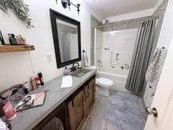 Bathroom with vanity, shower / bath combo, light tile patterned floors, and a textured ceiling - 