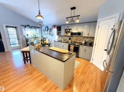 Kitchen with stainless steel appliances, pendant lighting, a kitchen island with sink, backsplash, and light wood-type flooring - 