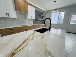 Kitchen featuring white cabinets, open shelves, light stone countertops, pendant lighting, and decorative backsplash - 