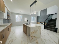 Kitchen with light stone counters, pendant lighting, light marble finish flooring, an island with sink, and brown cabinetry - 