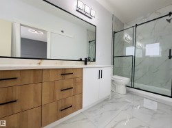 Bathroom featuring double vanity, light marble finish flooring, and a marble finish shower - 