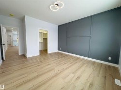 Unfurnished bedroom with a decorative wall, a spacious closet, and light wood-style flooring - 
