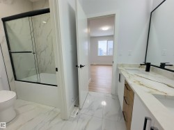 Full bathroom with double vanity, light marble finish floors, and combined bath / shower with glass door - 