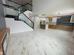 Unfurnished living room featuring stairway, light marble finish flooring, recessed lighting, and a towering ceiling - 