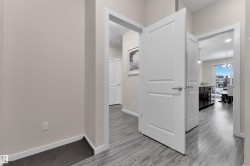 Hall featuring light wood finished floors and a chandelier - 