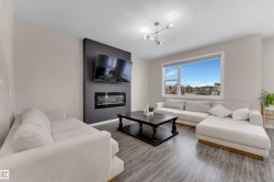 Living area featuring a large fireplace, wood finished floors, and a chandelier - 