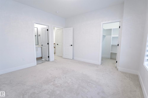 Unfurnished bedroom with light carpet, a walk in closet, and ensuite bath - 244 Rolston Wynd, Leduc, AB - Indoor Photo Showing Other Room