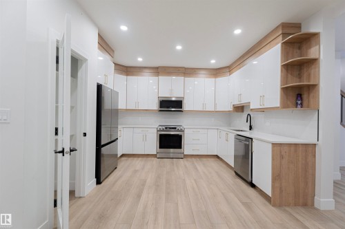 Kitchen featuring open shelves, appliances with stainless steel finishes, white cabinets, light wood-type flooring, and modern cabinets - 244 Rolston Wynd, Leduc, AB - Indoor Photo Showing Kitchen