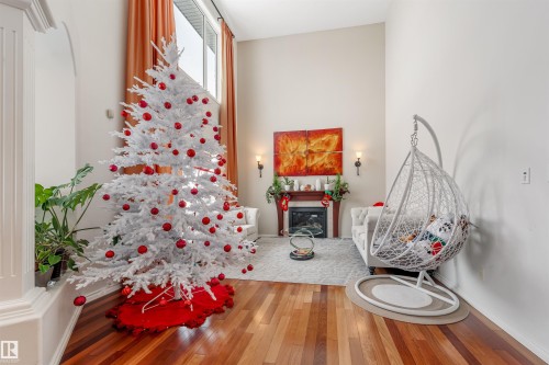 Sitting room featuring a glass covered fireplace and hardwood / wood-style floors - 20524 58 Avenue, Edmonton, AB - Indoor Photo Showing Other Room