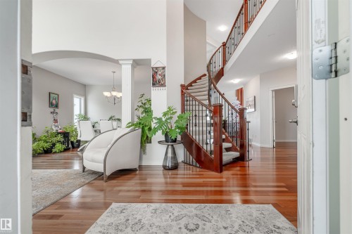 Entryway with light wood-style flooring, a towering ceiling, arched walkways, stairs, and a chandelier - 20524 58 Avenue, Edmonton, AB - Indoor Photo Showing Other Room