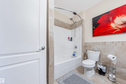 Bathroom featuring wainscoting, tile walls, bathtub / shower combination, and tile patterned flooring - 20524 58 Avenue, Edmonton, AB - Indoor Photo Showing Bathroom