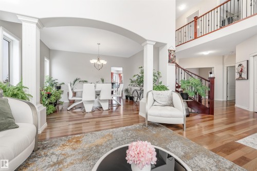 Living area featuring light wood-style flooring, a chandelier, arched walkways, ornate columns, and a towering ceiling - 20524 58 Avenue, Edmonton, AB - Indoor Photo Showing Living Room