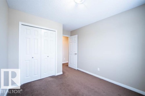 Unfurnished bedroom featuring dark colored carpet, a closet, and a textured ceiling - 3117 Arthurs Crescent, Edmonton, AB - Indoor