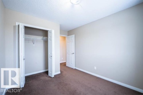 Unfurnished bedroom featuring dark carpet, a closet, and a textured ceiling - 3117 Arthurs Crescent, Edmonton, AB - Indoor Photo Showing Other Room