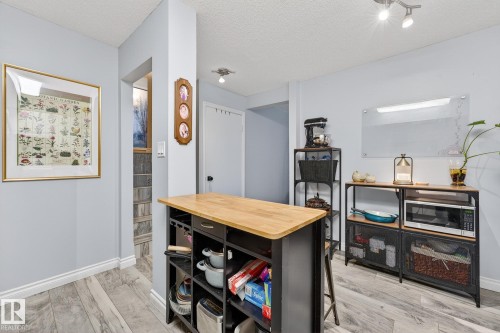 Kitchen with butcher block countertops, a textured ceiling, stainless steel microwave, and light wood-style floors - 7 Grandview Ridge, St. Albert, AB - Indoor Photo Showing Other Room