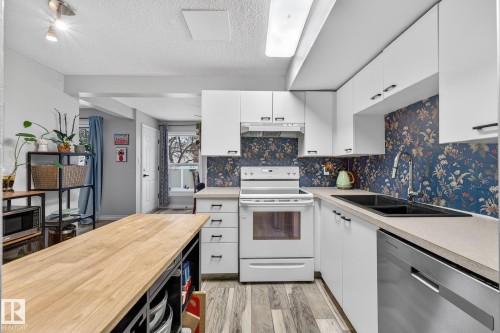 Kitchen with stainless steel appliances, white cabinets, butcher block countertops, a textured ceiling, and decorative backsplash - 7 Grandview Ridge, St. Albert, AB - Indoor Photo Showing Kitchen With Double Sink