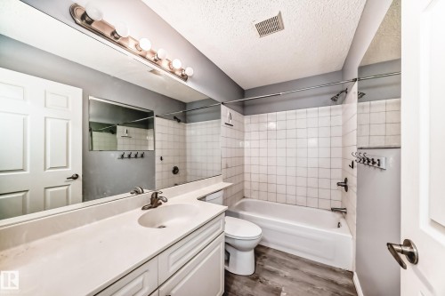 Bathroom with vanity, a textured ceiling, bathing tub / shower combination, and dark wood finished floors - 507 11716 100 Avenue, Edmonton, AB - Indoor Photo Showing Bathroom