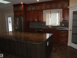 Kitchen featuring stainless steel appliances, dark stone countertops, decorative backsplash, a kitchen island, and ornamental molding - 