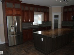 Kitchen featuring stainless steel fridge, dark stone counters, ornamental molding, backsplash, and a center island - 