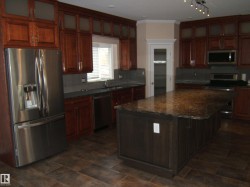 Kitchen featuring appliances with stainless steel finishes, decorative backsplash, ornamental molding, dark stone counters, and a center island - 