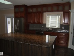 Kitchen with crown molding, appliances with stainless steel finishes, dark stone countertops, a center island, and decorative backsplash - 