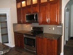 Kitchen featuring appliances with stainless steel finishes, dark stone counters, decorative backsplash, and glass insert cabinets - 