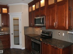Kitchen with stainless steel appliances, crown molding, and dark stone countertops - 
