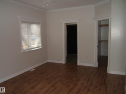 Unfurnished bedroom with a spacious closet, dark wood-style floors, ornamental molding, and a ceiling fan - 