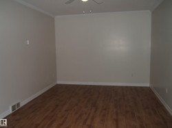 Empty room featuring dark wood-style floors, ornamental molding, and a ceiling fan - 