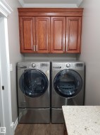 Laundry room with cabinet space, dark wood-type flooring, separate washer and dryer, and crown molding - 