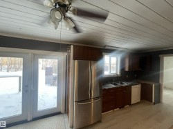 Kitchen with freestanding refrigerator, dark countertops, dishwasher, a ceiling fan, and dark brown cabinets - 