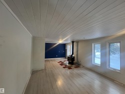 Unfurnished living room featuring wood ceiling, a wood stove, and light wood-style flooring - 