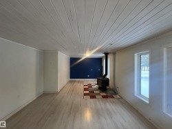 Unfurnished living room with wood ceiling, a wood stove, and light wood-style flooring - 