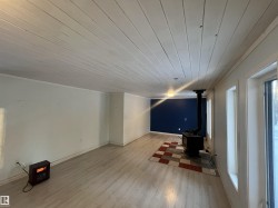 Spare room featuring a wood stove, wooden ceiling, light wood-style floors, and crown molding - 