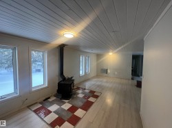 Unfurnished living room with wooden ceiling, light wood finished floors, and a wood stove - 