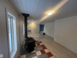 Basement with a wood stove, wood ceiling, wood finished floors, and crown molding - 