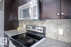 Kitchen with stainless steel appliances, light stone countertops, tasteful backsplash, and dark brown cabinetry - 