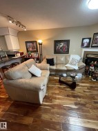 Living area with a textured ceiling, wood-type flooring, a lit fireplace, and track lighting - 