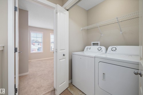 Laundry room featuring light colored carpet, a textured ceiling, and washing machine and clothes dryer - 5247 20 Avenue Sw, Edmonton, AB - Indoor Photo Showing Laundry Room