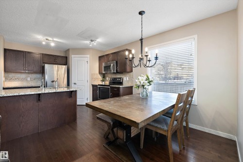 Dining room with dark wood finished floors, a chandelier, and a textured ceiling - 5247 20 Avenue Sw, Edmonton, AB - Indoor