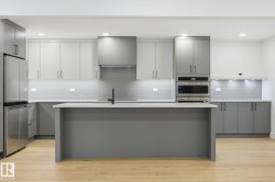 Kitchen with gray cabinets, stainless steel appliances, tasteful backsplash, a kitchen island with sink, and recessed lighting - 