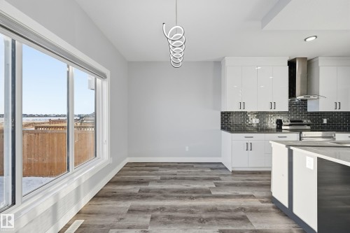 Kitchen with white cabinets, wall chimney range hood, light wood-type flooring, and electric stove - 829 Morris Avenue, Leduc, AB - Indoor Photo Showing Kitchen